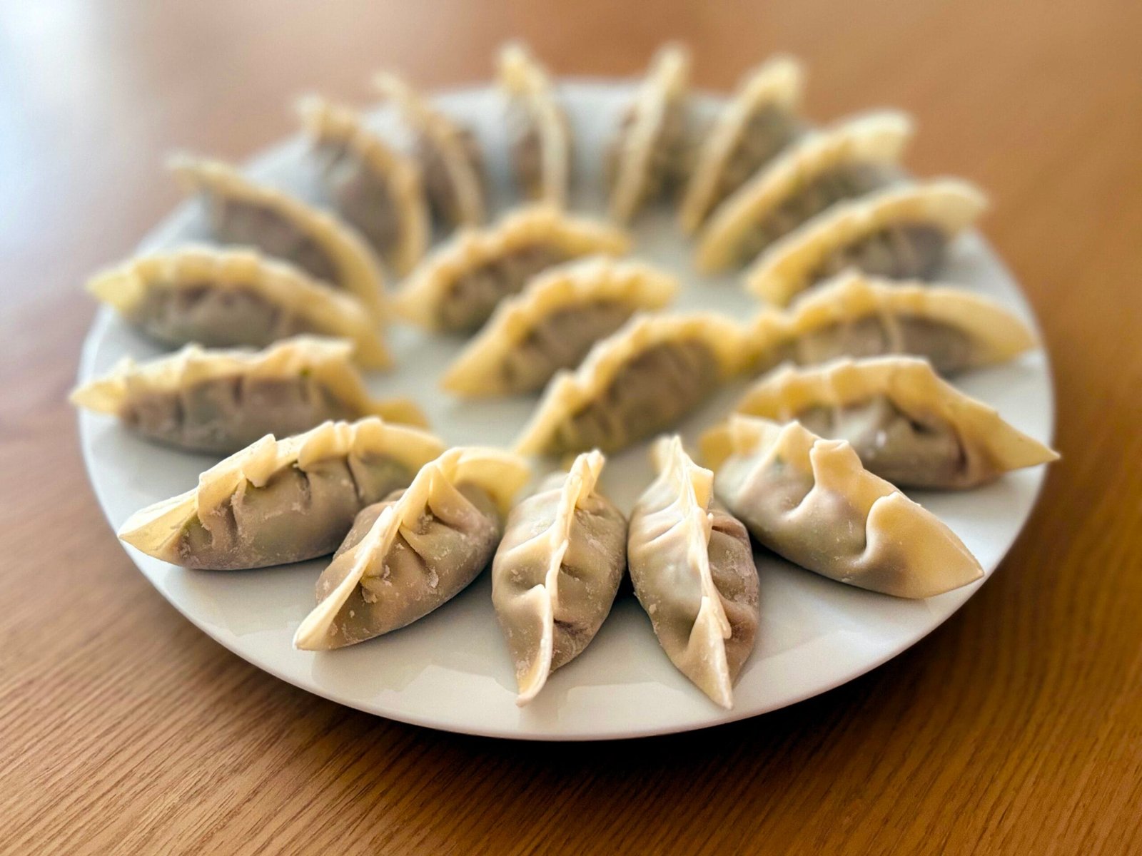 A plate of 20 or so freshly made raw gyoza.