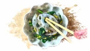 Lotus root and chrysanthemum greens salad being garnished with bright yellow flower petals.