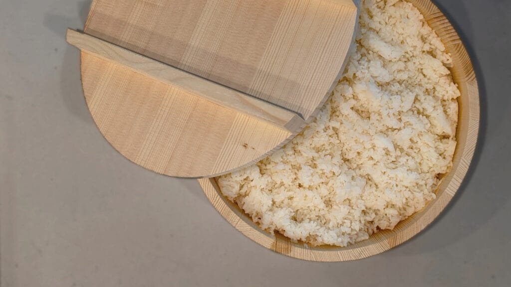 Overhead photograph of steamed rice in a traditional Japanese ohitsu rice bucket made from cedar.